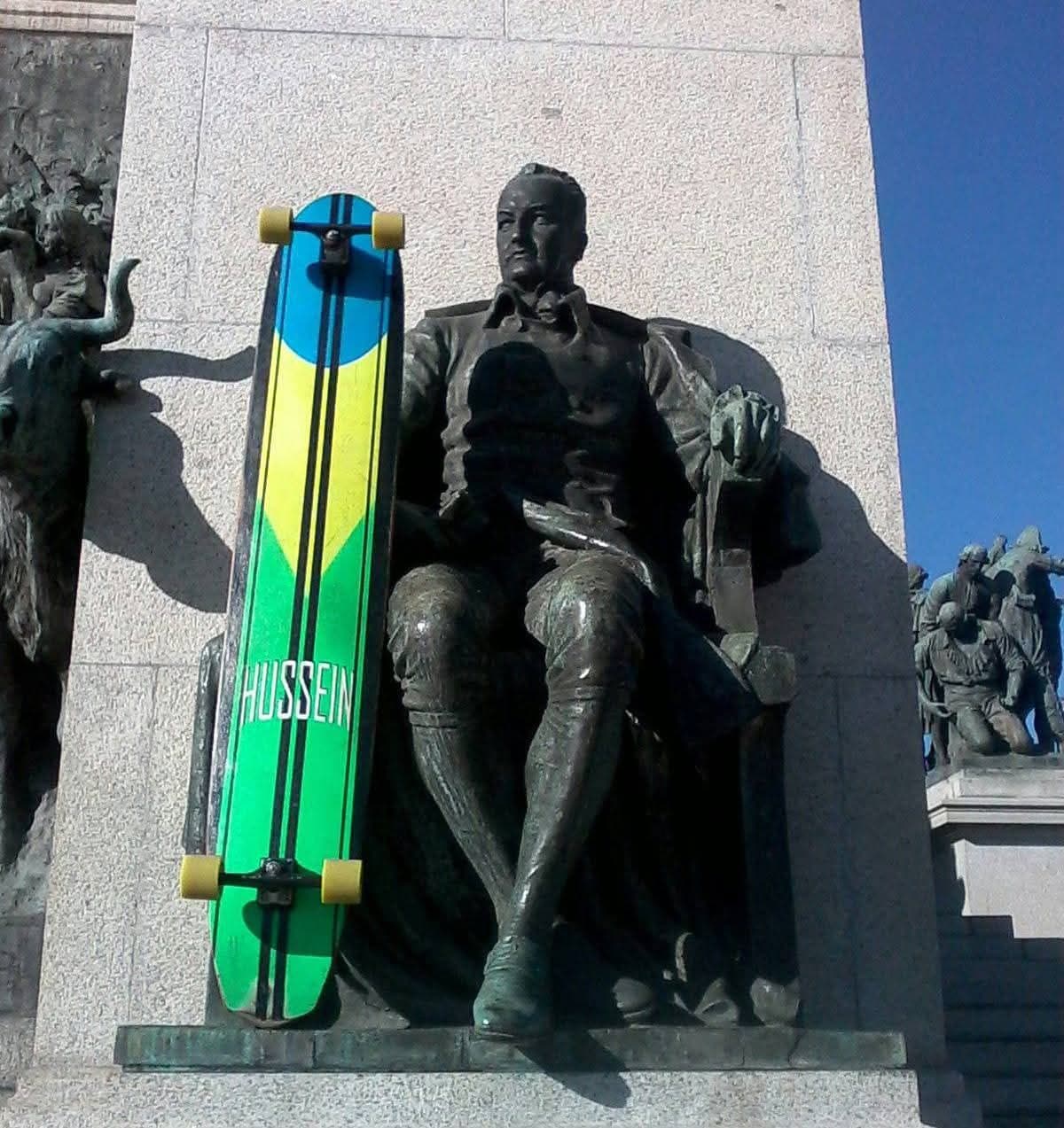Board verde-amarelo Hussein encostado em estátua — São Paulo