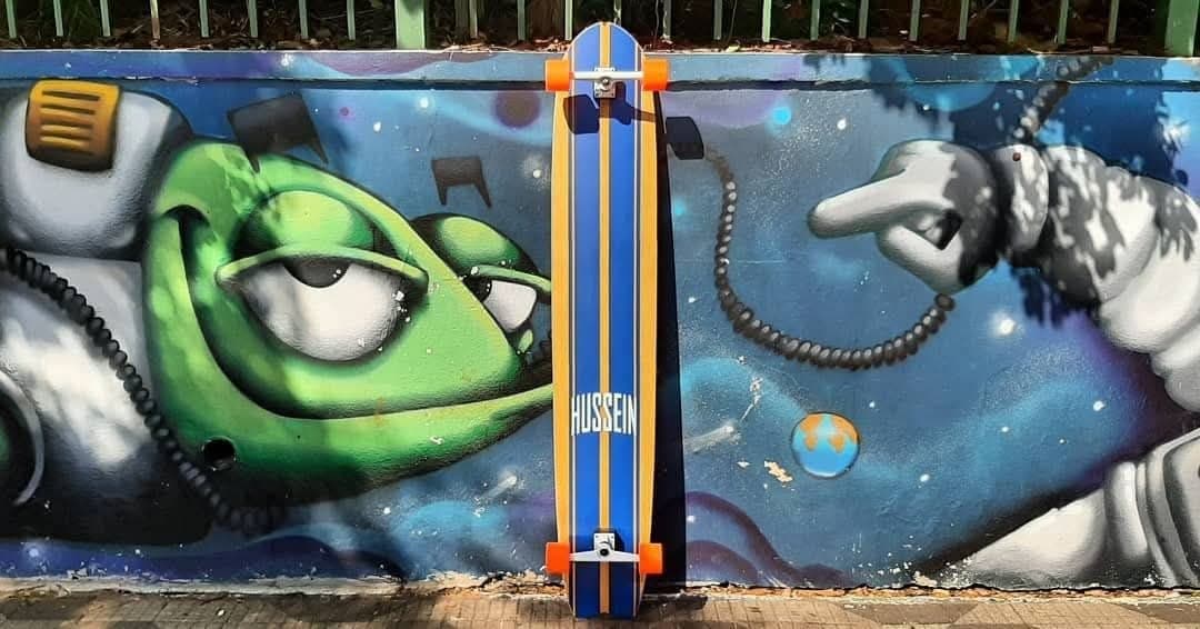 Longboard encostado em muro de grafite